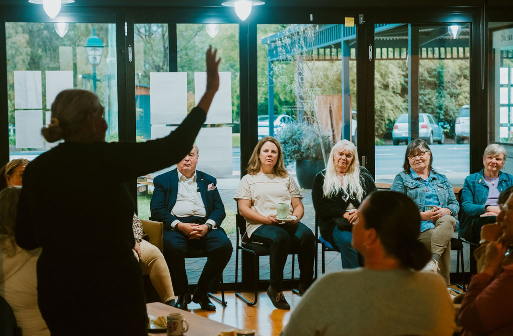 A room of people watch a speaker at the front of the room speaking in the cospace