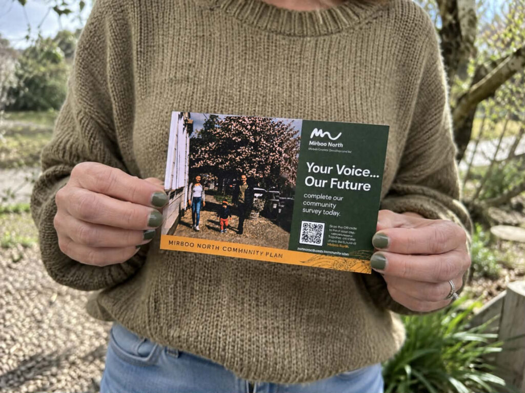 Woman holds postcard of community planning survey